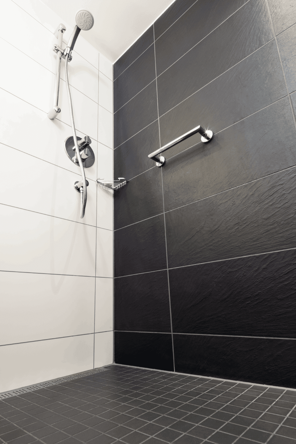 Low angle view of a modern shower enclosure, with chrome fixtures. matte finish floor tile