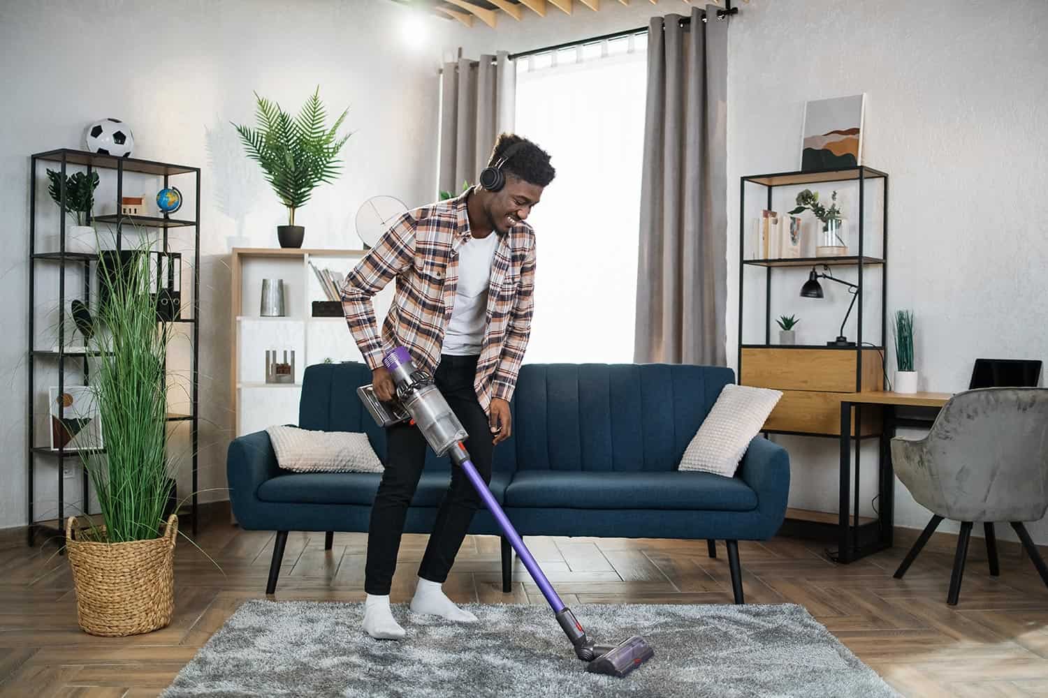 Man in headphones cleaning carpet with vacuum cleaner