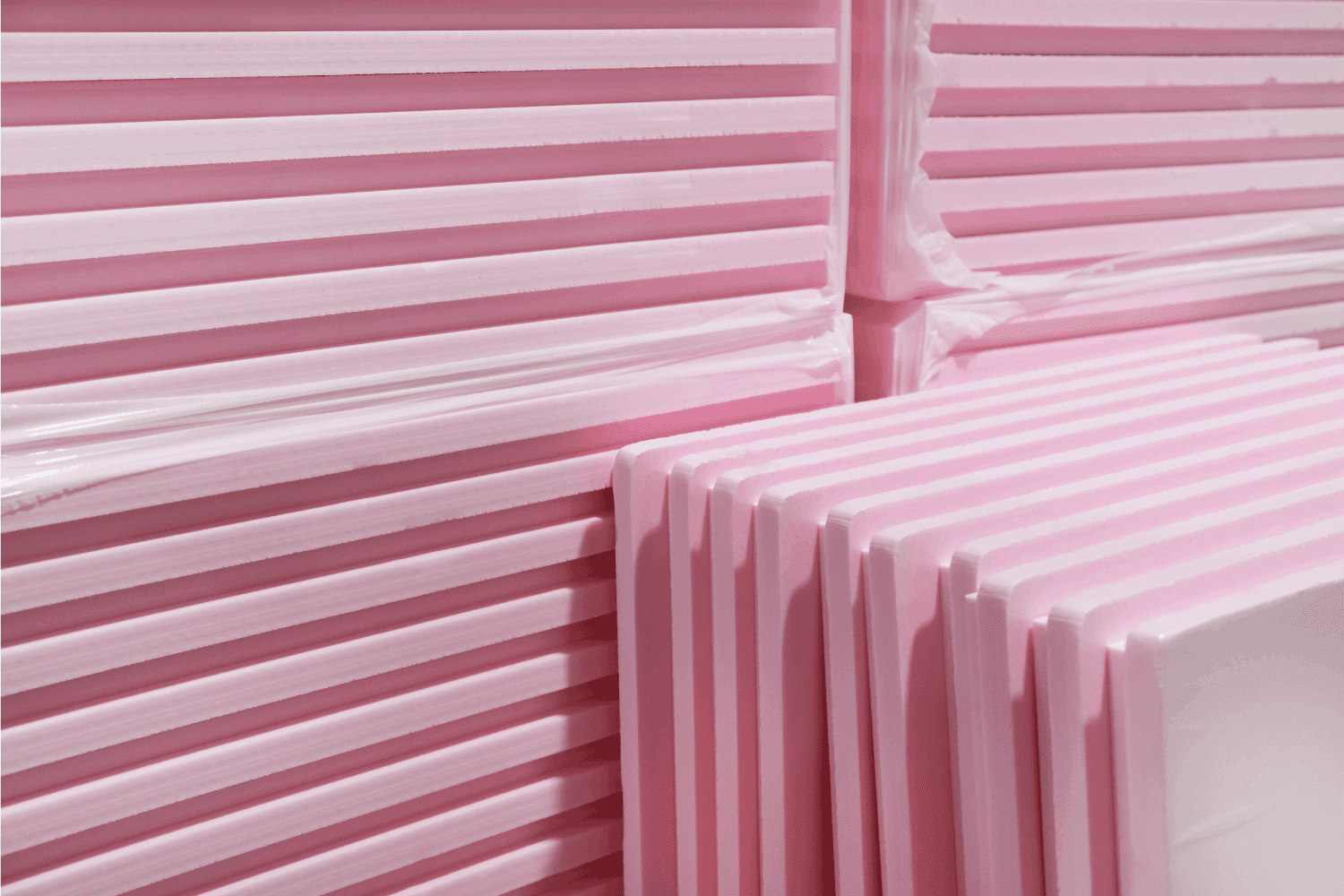 Pink Extruded Polystyrene XPS foam thermal insulation boards stacked in construction site.