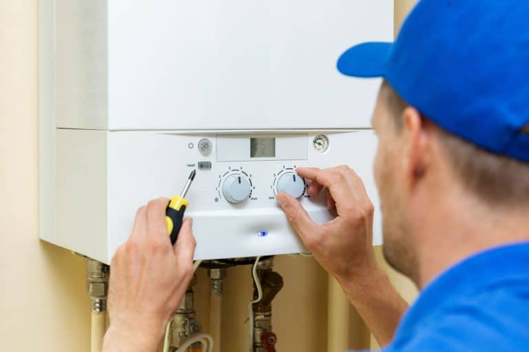 Repair technician checking the knobs of the water heater, How To Drain A Gas Water Heater