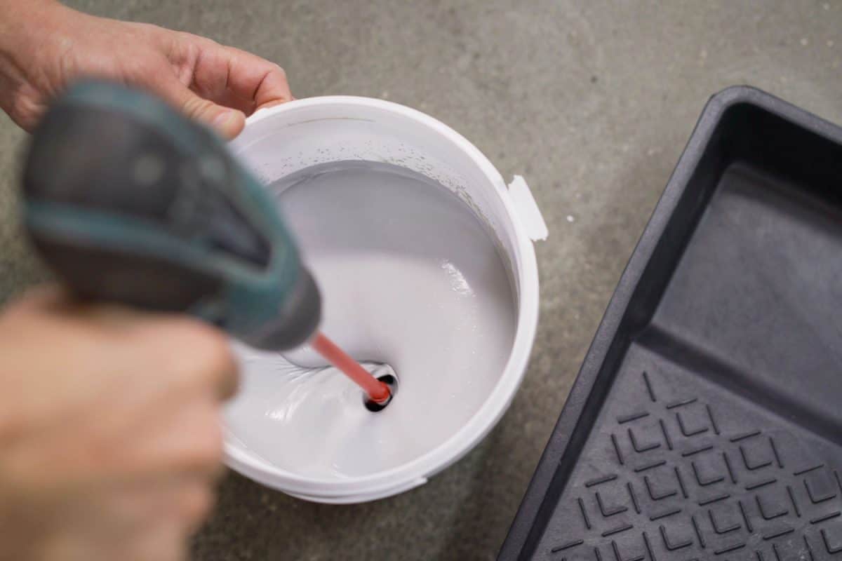 Using a drill to mix the bucket of paint with another color