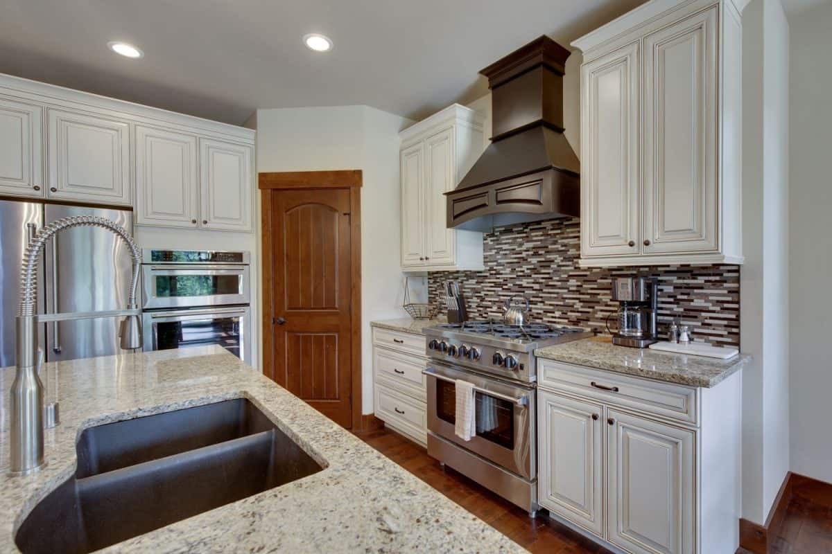White cabinets and cupboards with a breakfast bar with marble countertop