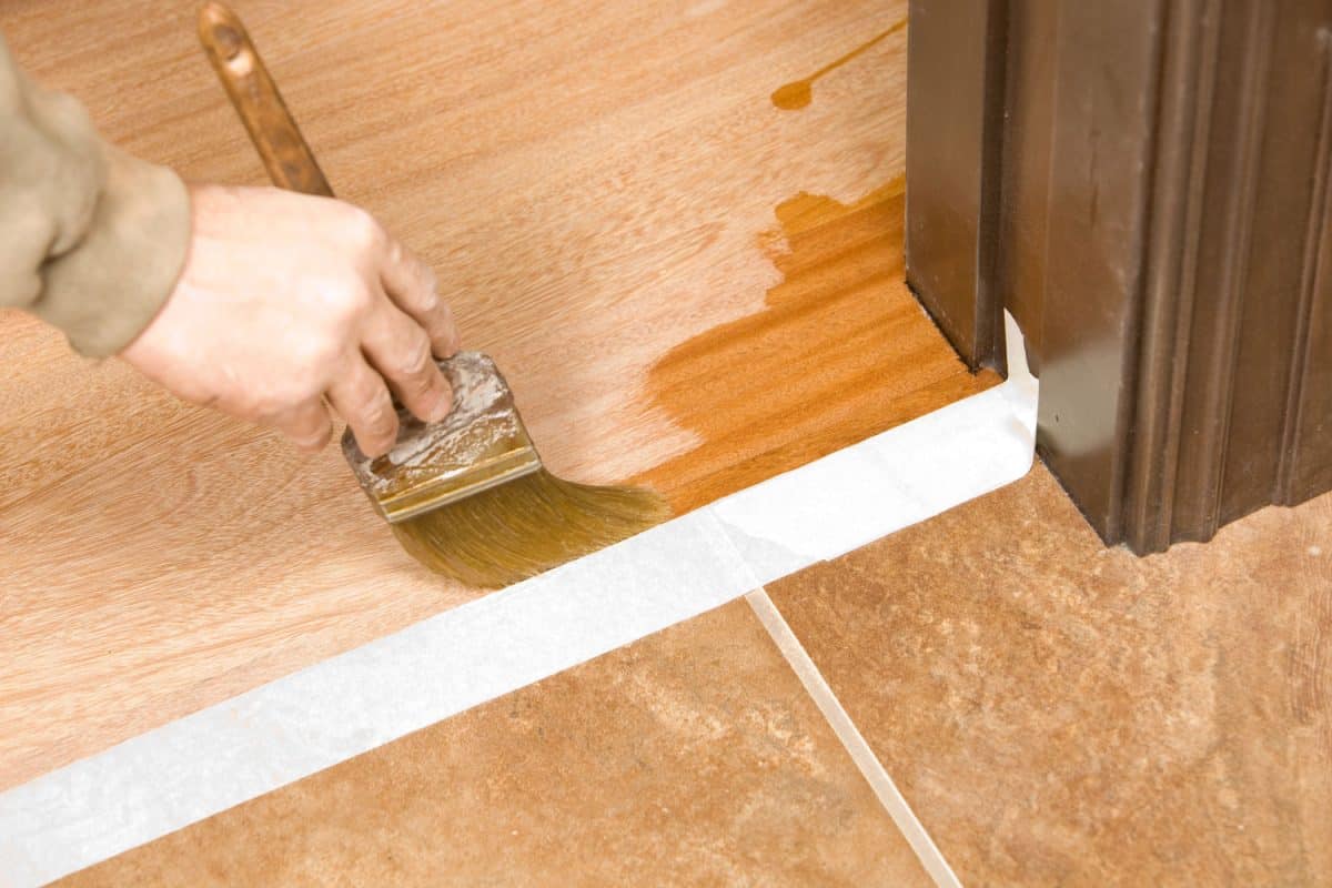 Worker applying polyurethane coating on the flooring