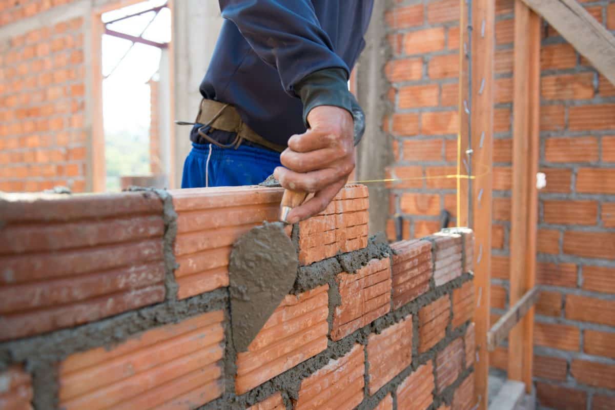 Bricklayer properly laying bricks at a house under construction