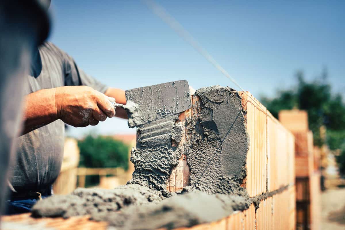 Bricklayer putting mortar on the bricks