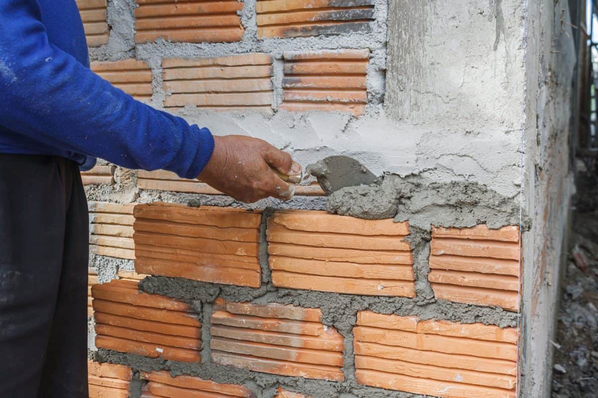 Man putting mortar on the bricks and properly laying it