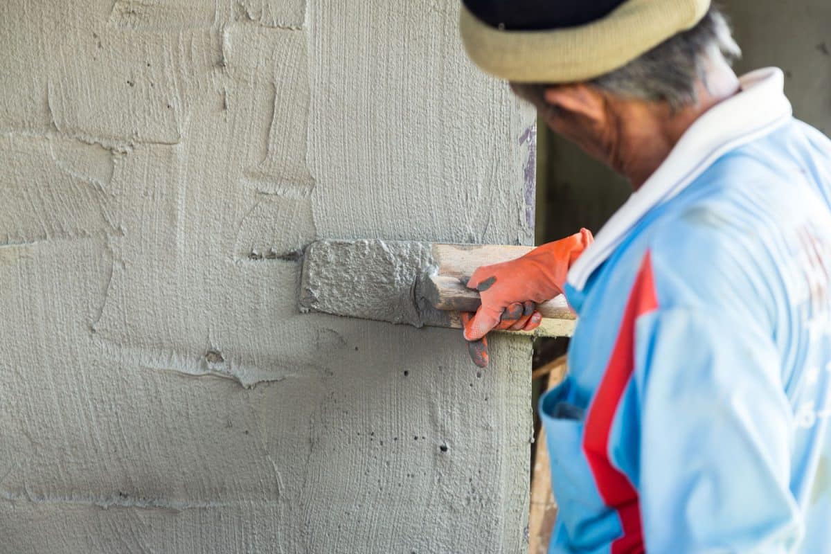 Mason spreading plastering mortar on the side of a wall