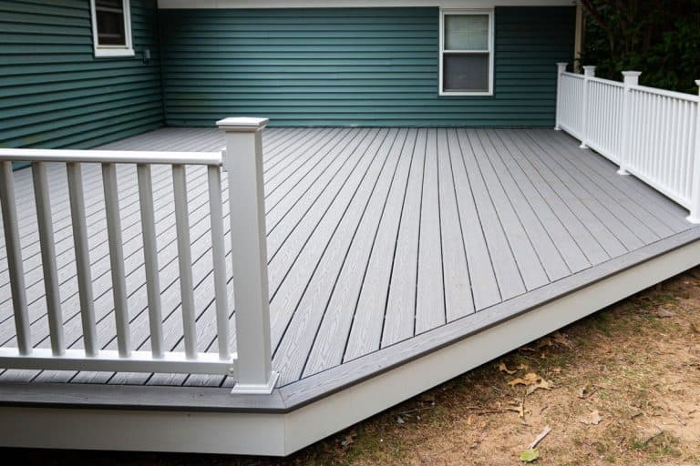 New composite deck on the back of a house with green vinyl siding.with whie railings, How Much Does A Deck Weigh