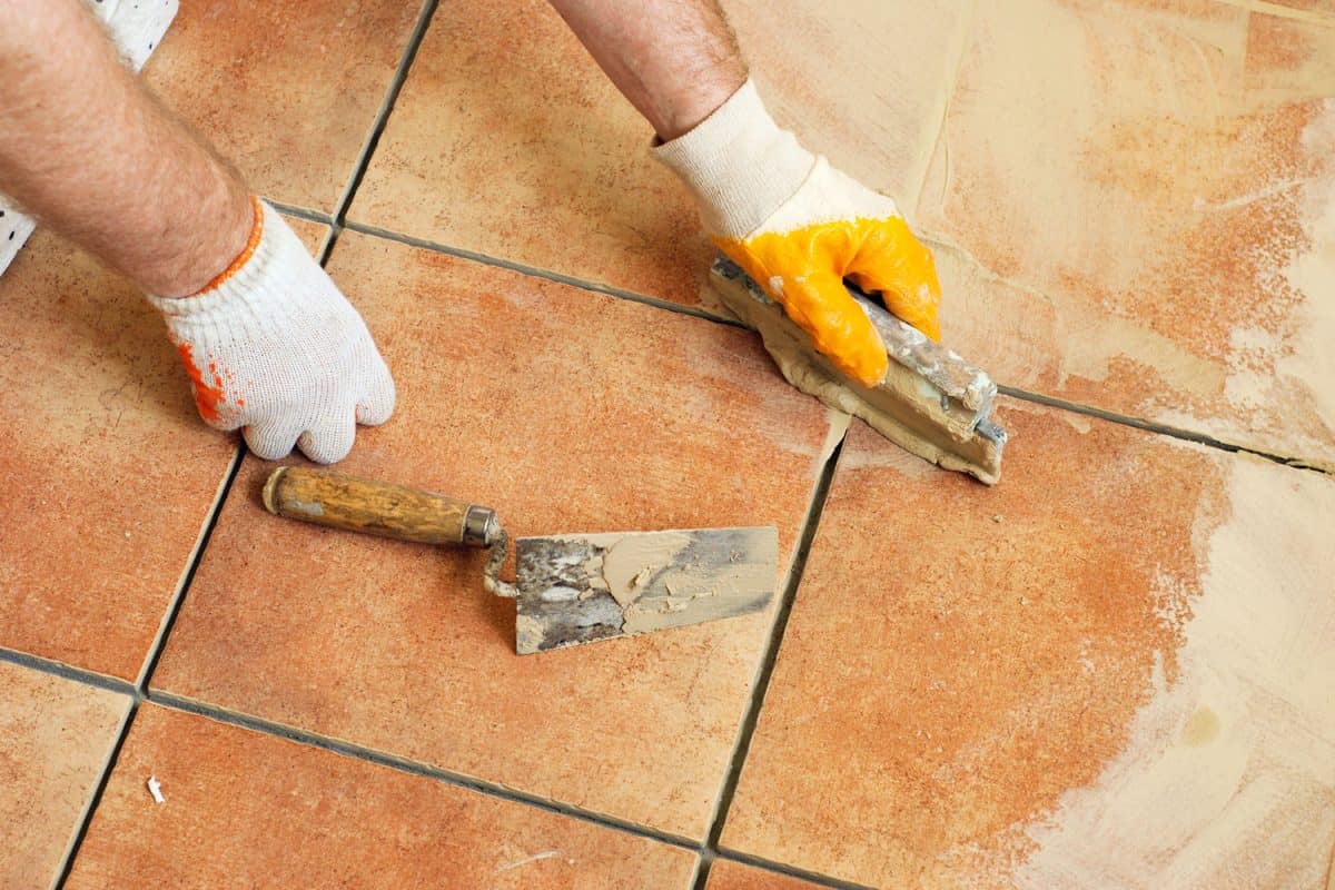 Worker putting grout on the tiles
