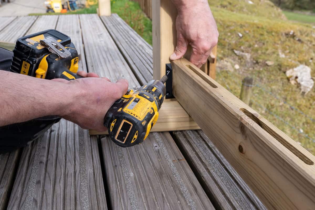 carpenter working outdoors, building wooden decking on the side of family hom