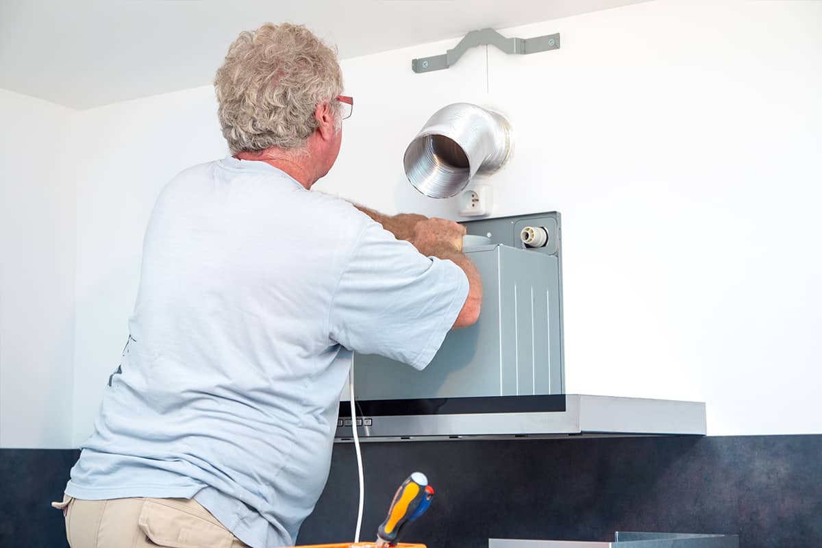 Fitter men installing range hood in new kitchen