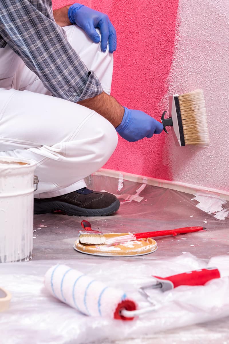 Worker painting a wall with a red color