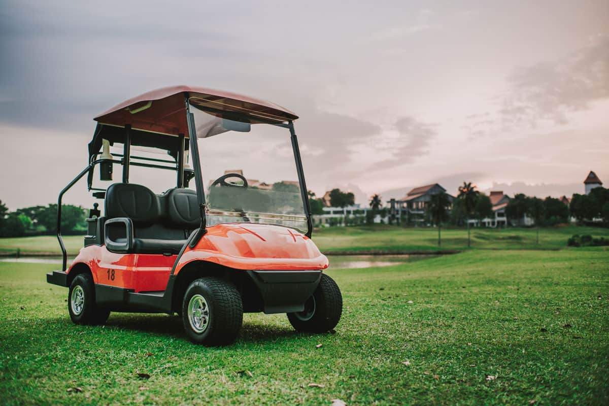 A red golf cart in the golf course during sunset