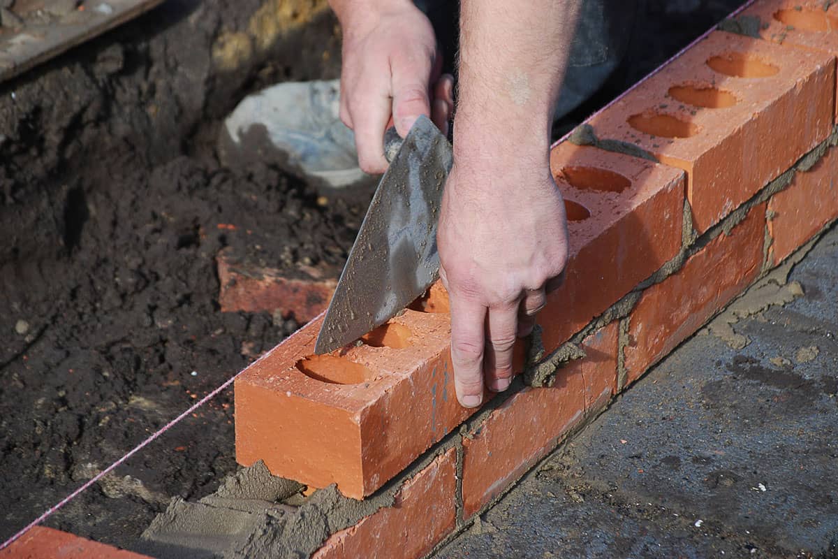 Brick plastering with a worker hand aligning the bricks