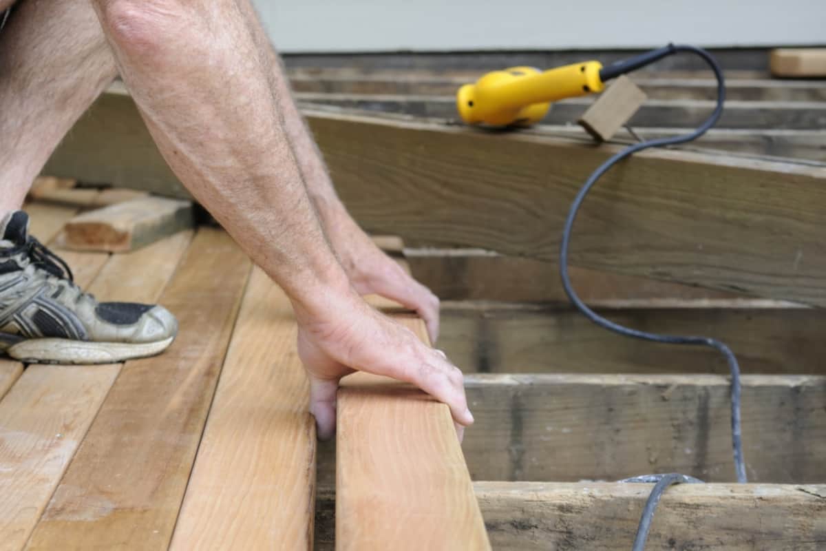 Check The Quality Of Your Deck's Railings And Stairs - Carpenter installing new wood decking.