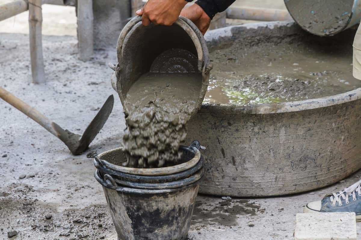 Construction worker put cement on a bucket