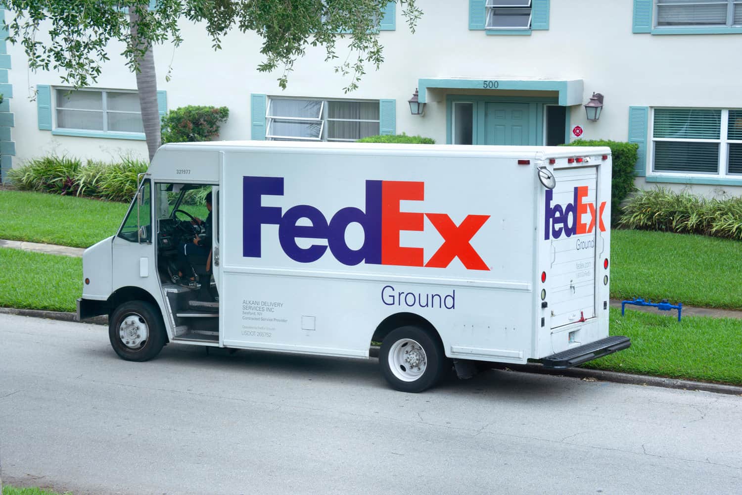 FedEx truck van parked on side of road to deliver ground delivery packages to someone who lives in an apartment building.