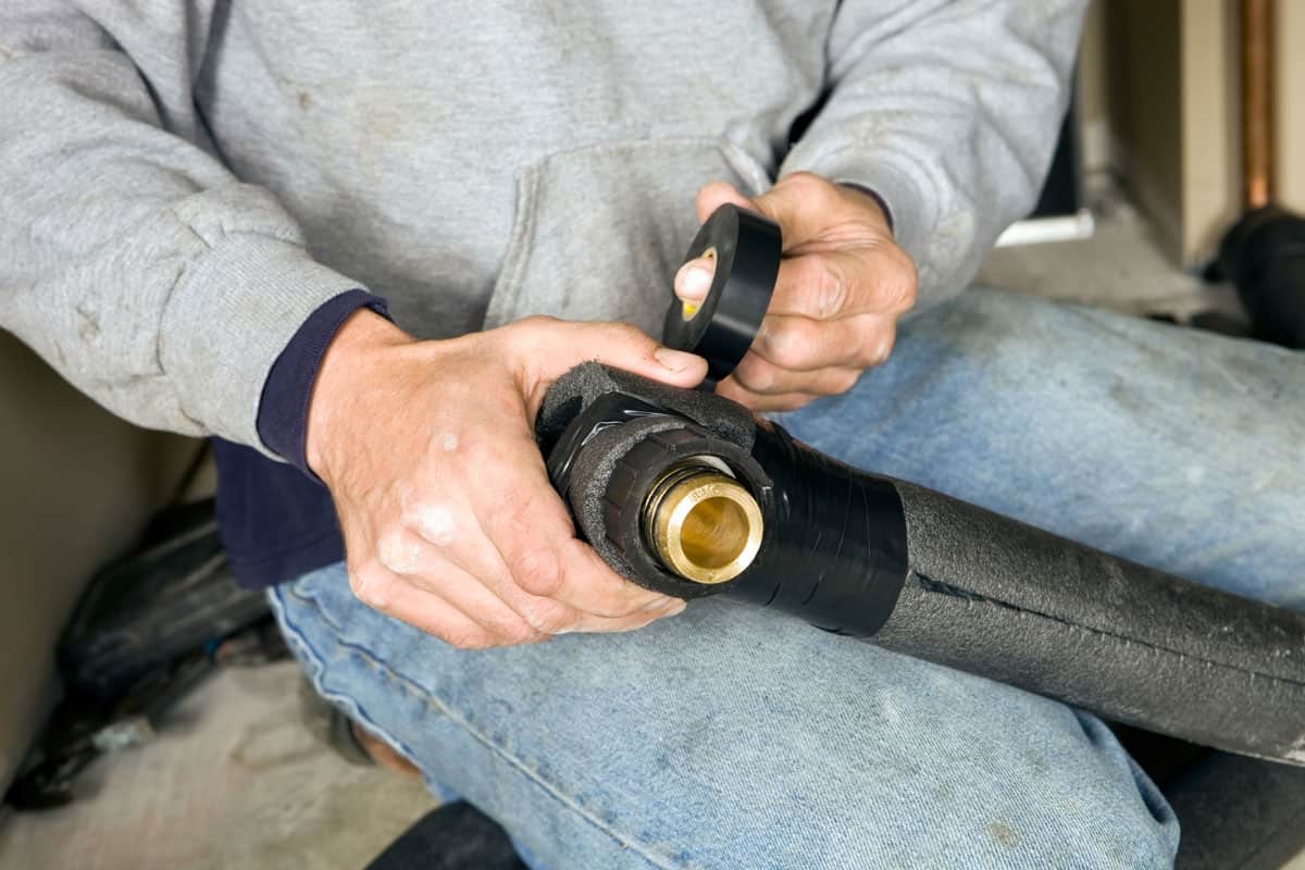 Plumber Fastening Pipe Insulation with heat tape