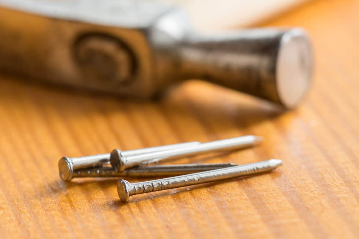 Small nails and carpenter hammer on a wooden worktable