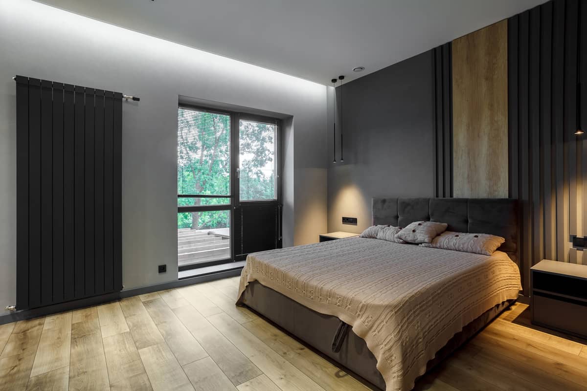 Interior of an ultra modern bedroom with ceramic tile flooring with matching gray walls and brown themed beddings