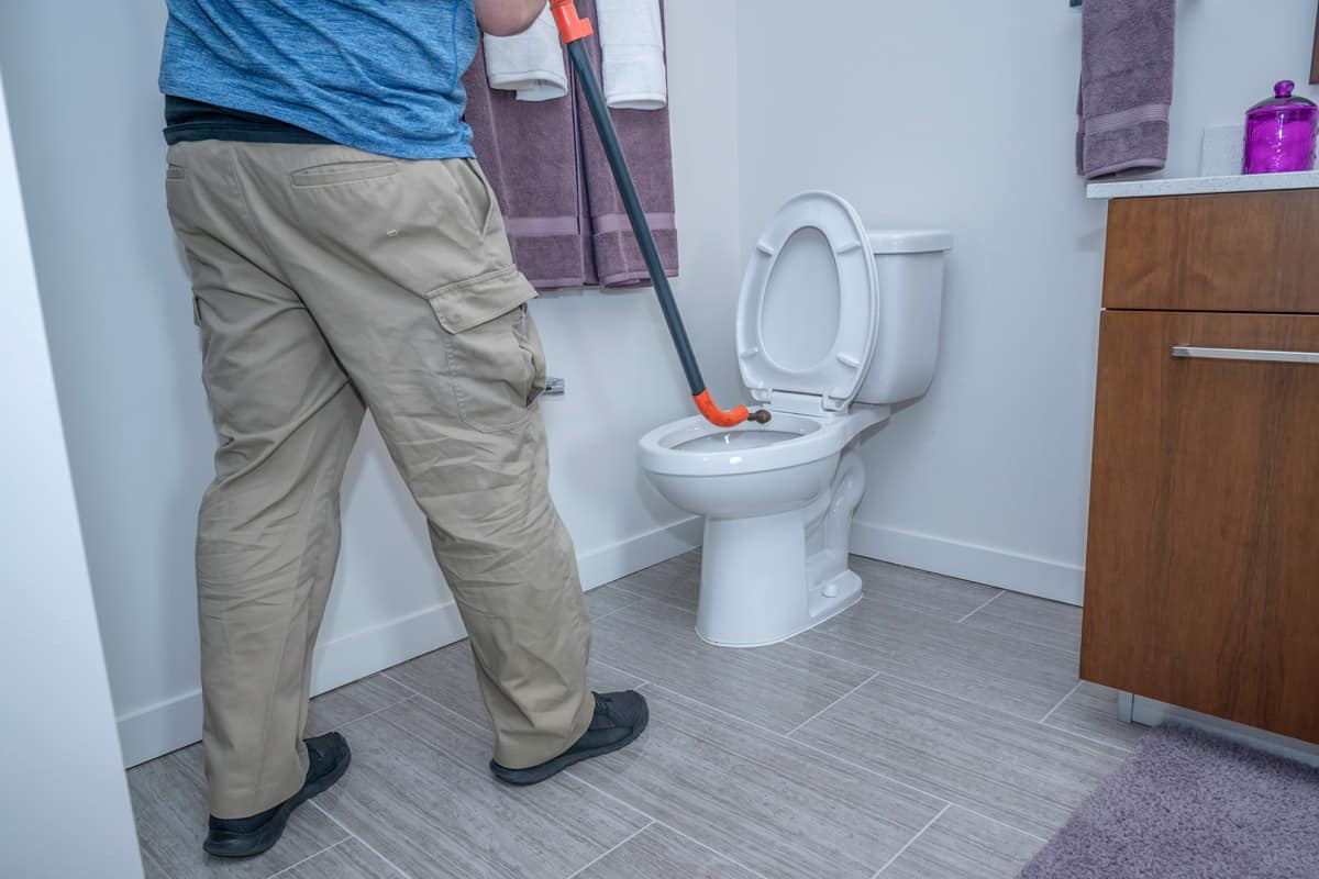 Plumber using a toilet auger