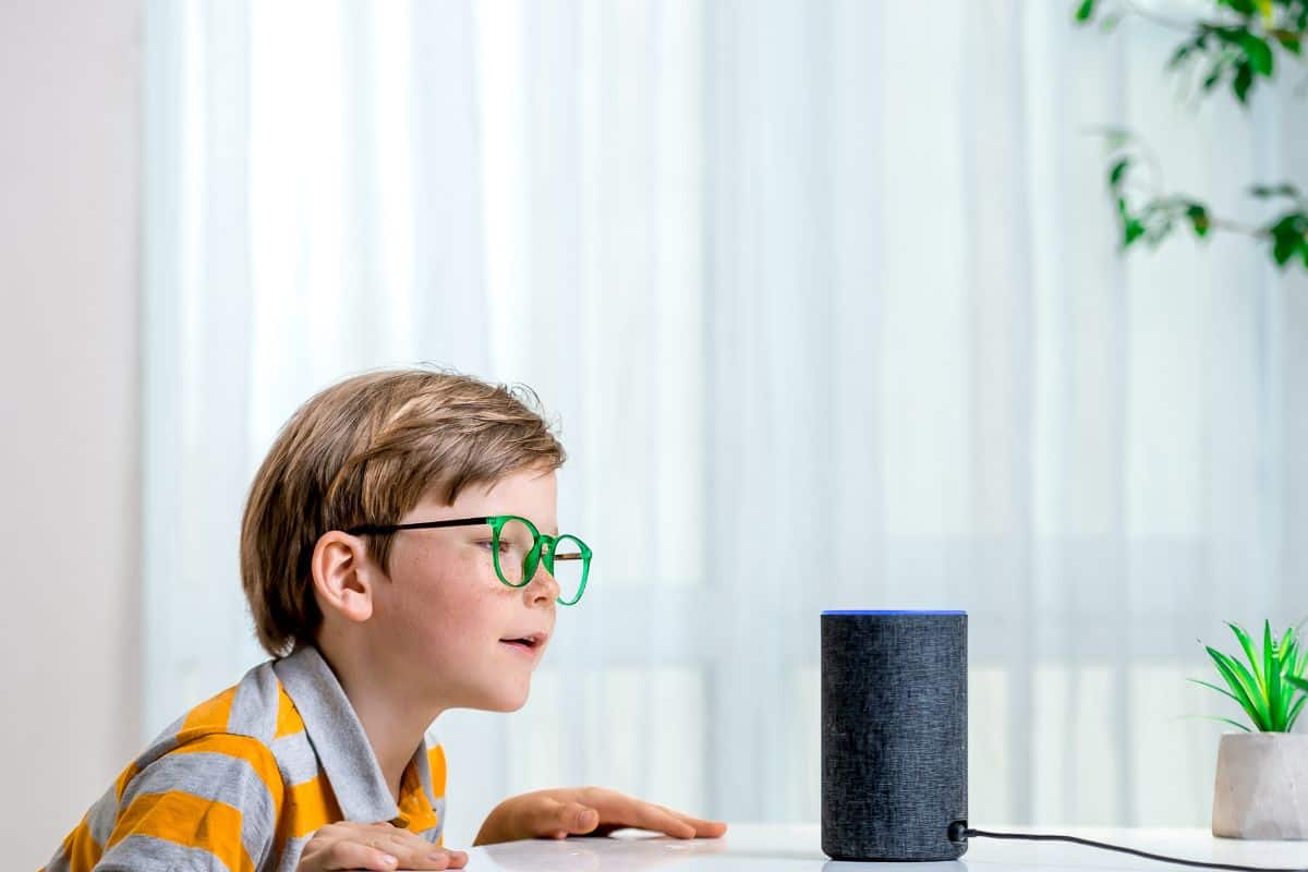 Voice controlled smart speaker. Little kid girl talking to talking to Amazon Alexa Echo Dot. Education programme for child. Boy talking to Alexa and give it orders and commands what to switch on