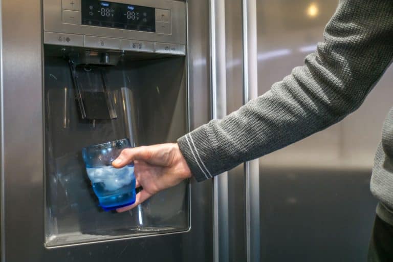 photo of a man wearing grey long sleeves getting ice and water on a whirlpool refrigerator, Whirlpool Refrigerator Not Making Ice But Water Works - What To Do?