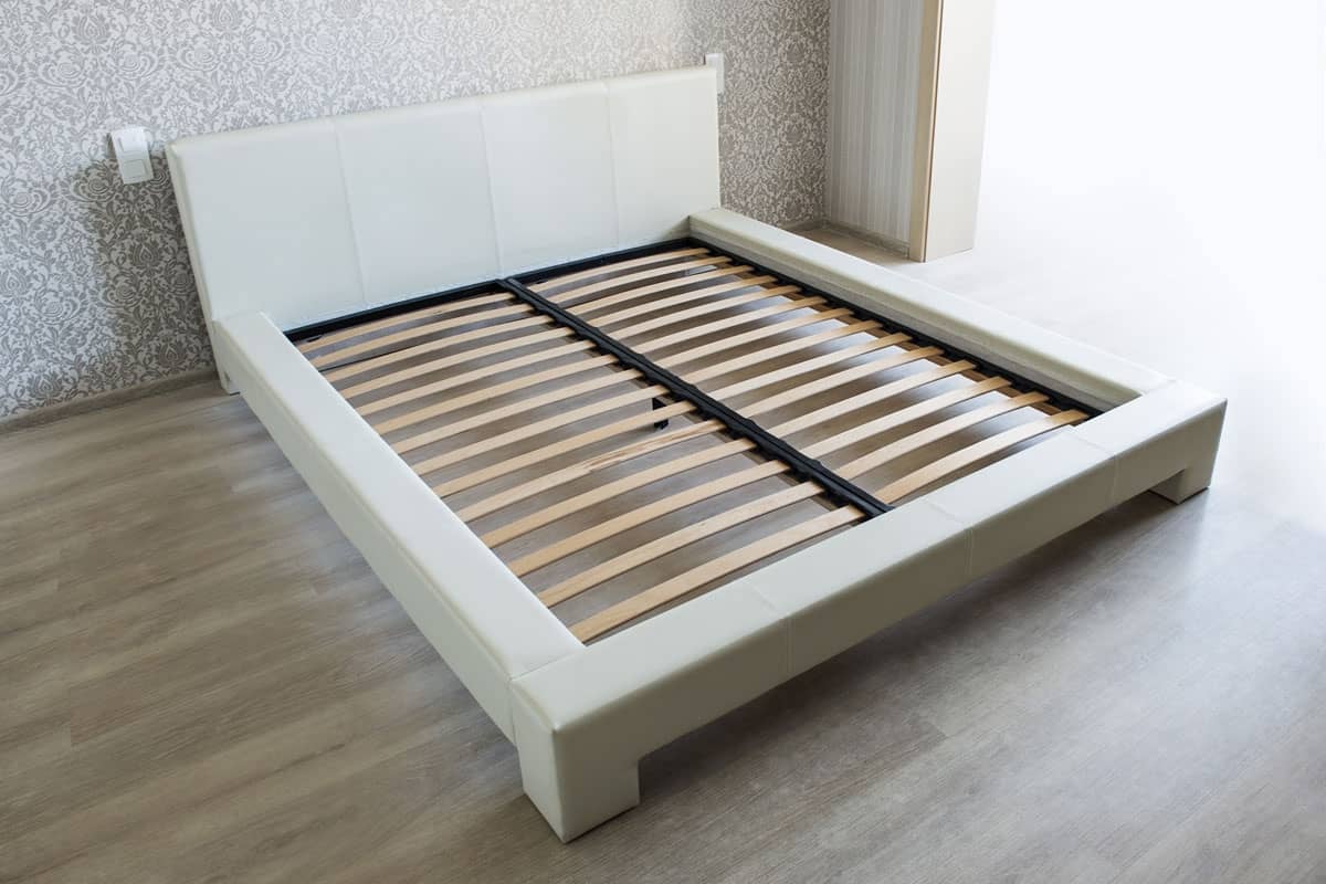 Bed in bedroom with wooden slats without mattress