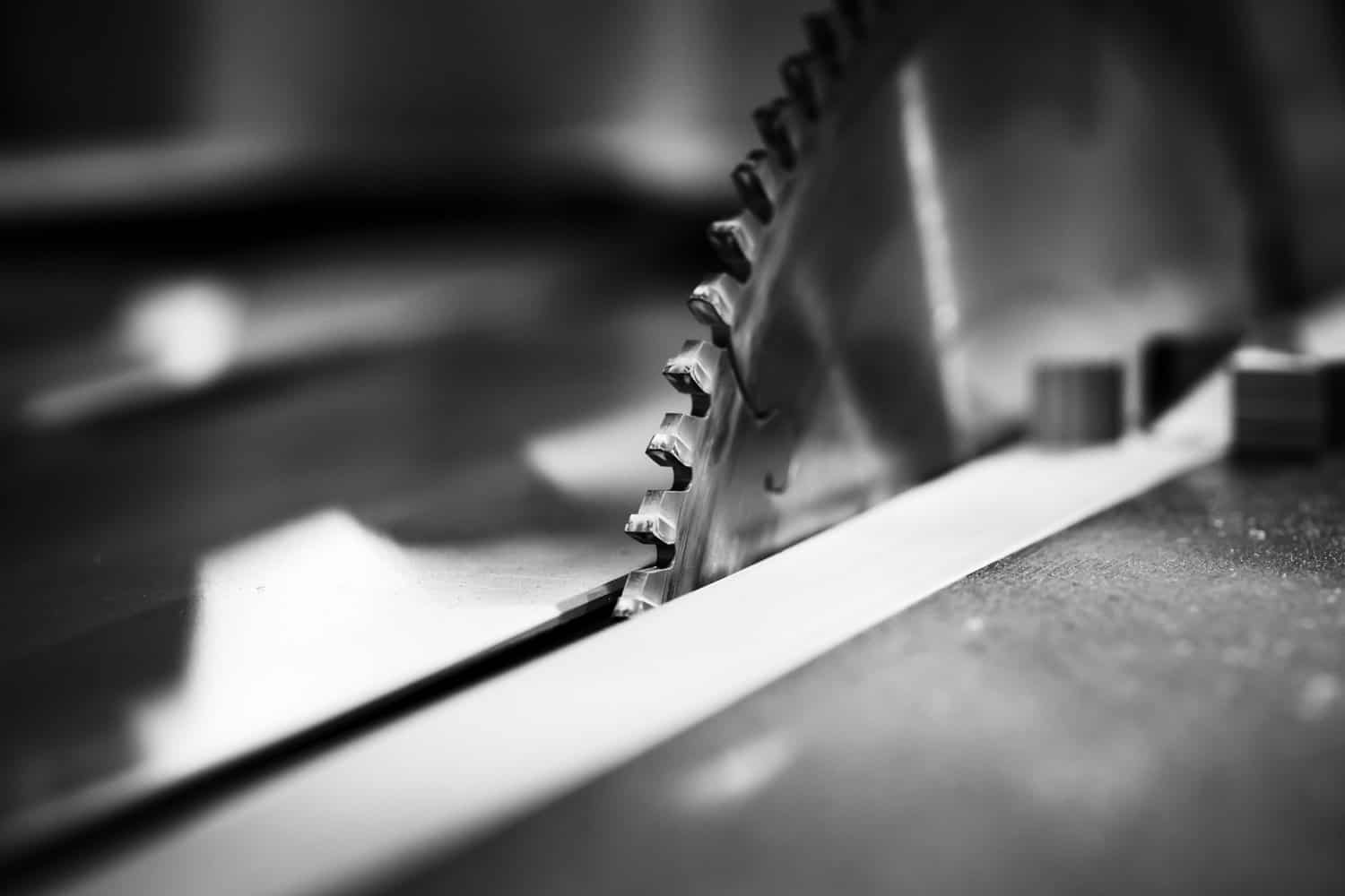 Circular table saw disc with carbide teeth, close-up black and white photo with selective focus