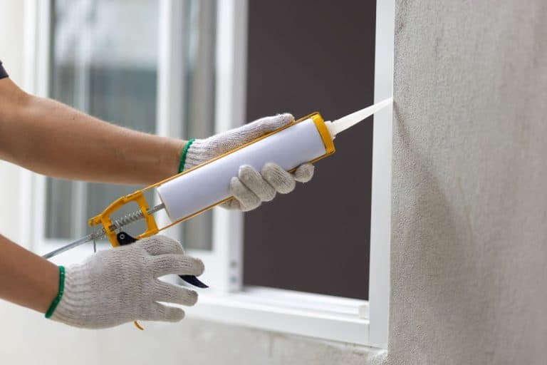 Construction worker using silicone sealant caulk the outside window frame. - How To Fill A Big Gap With Silicone