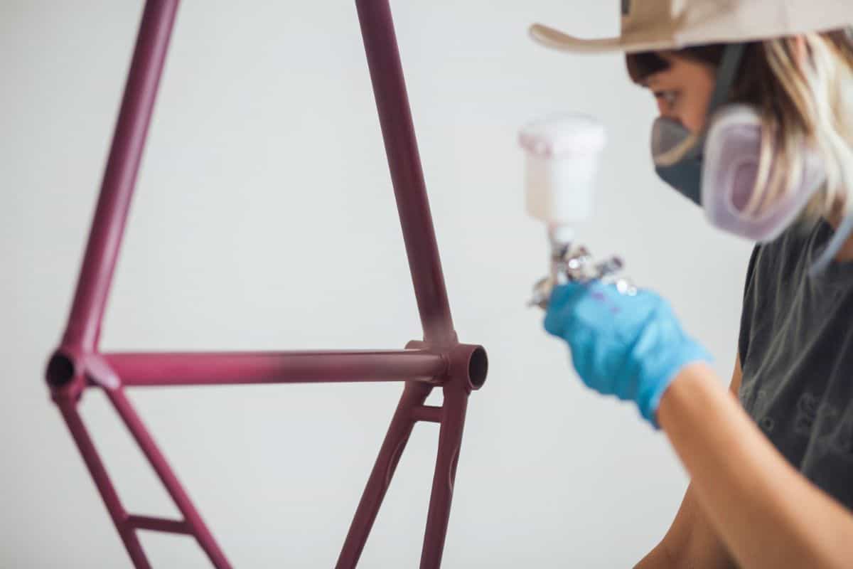 Funky modern woman painting bicycle frame
