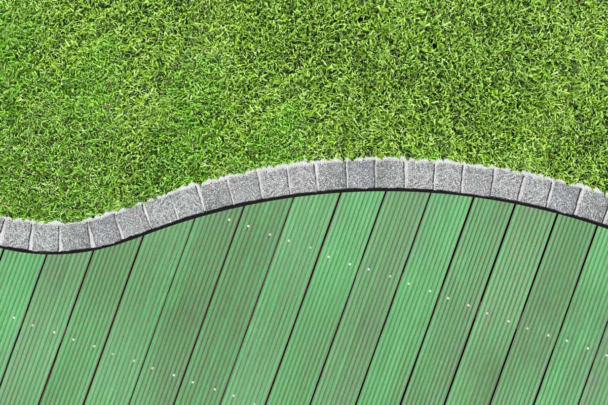 Green wooden garden decking and curved grass lawn boarder.