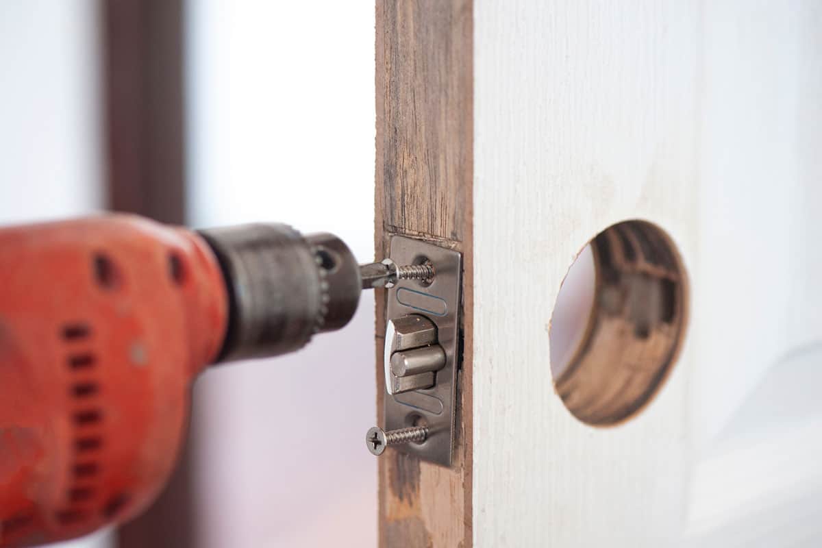 Handy man drilling the screws of a door lock