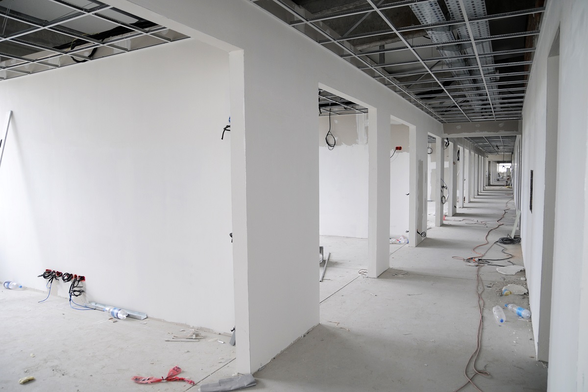 Inside of a building site. Corridor with pipes and wires, cables and conduits. Work in progress.