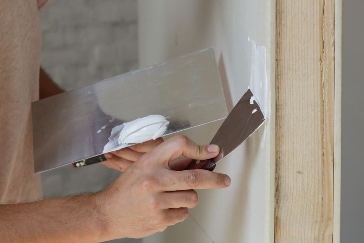 Man plastering wall with putty-knif