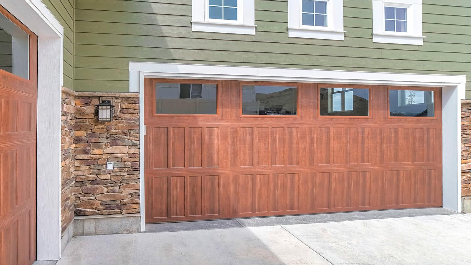 Panorama wooden garage doors with window panels and wall lamp
