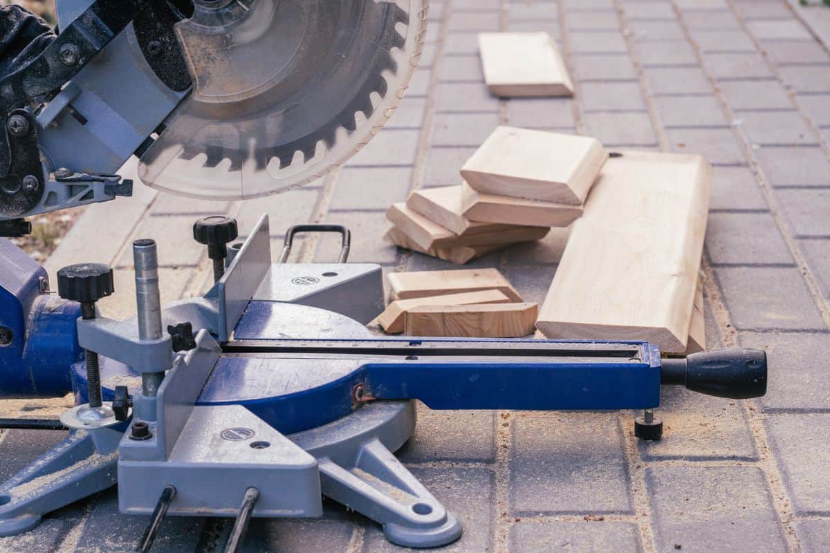 Professional miter saw on paving slabs with trim planks for house cladding. Construction and repair concept