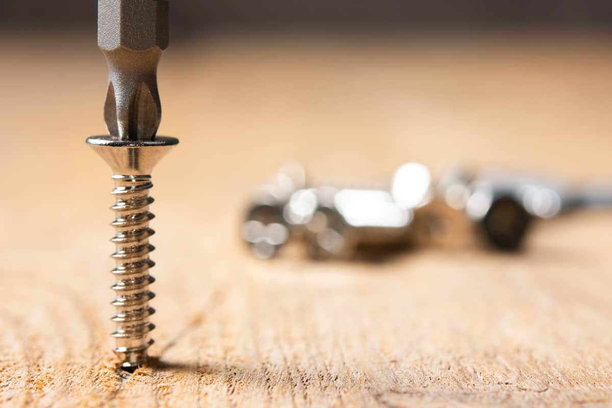Screws screwed into wooden plank stock photo. Screws close up on wooden table.