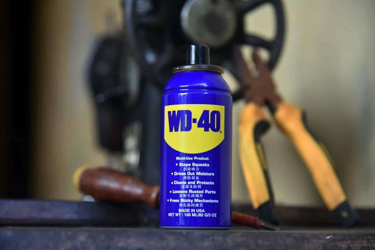 WD 40 oil, with a tong and screw driver placed on the old sewing machine
