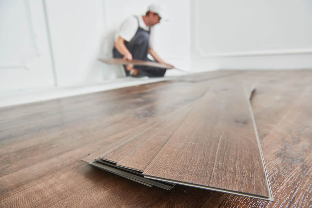 worker-laying-vinyl-floor-covering-home