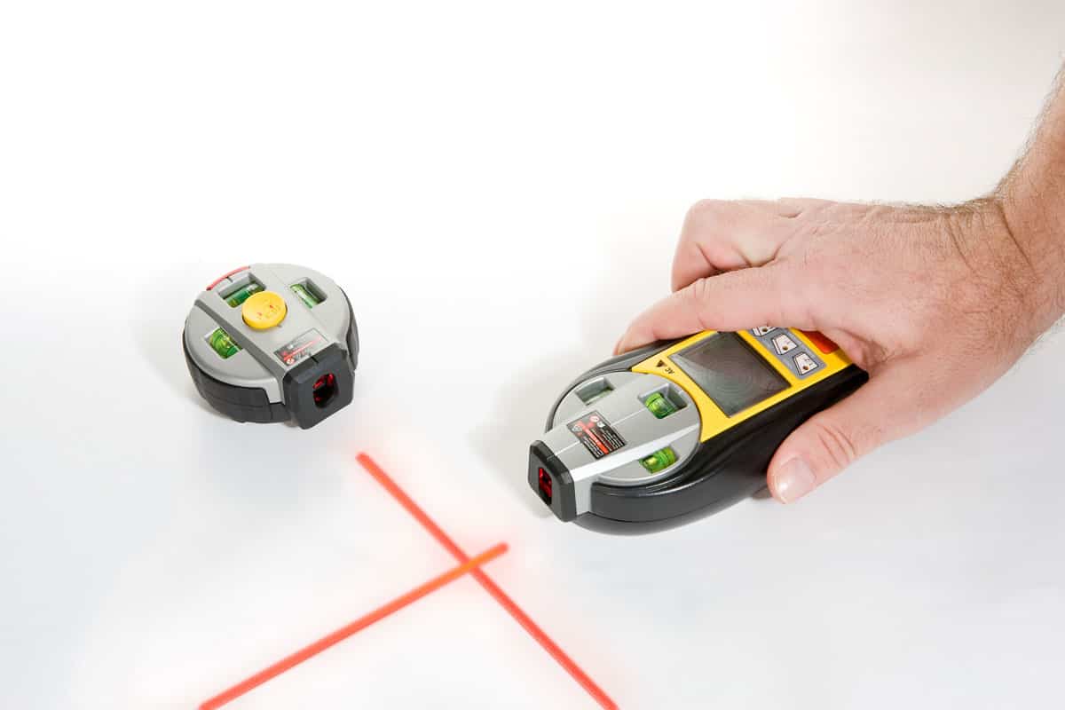 Using a stud finder and a laser designator for making guide in laying out tiles
