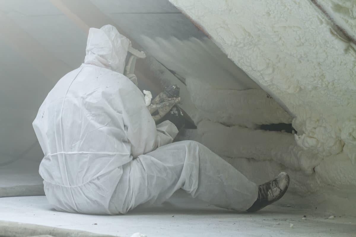 spray polyurethane foam for roof - technician spraying foam insulation using plural component gun for polyurethane foam, inside