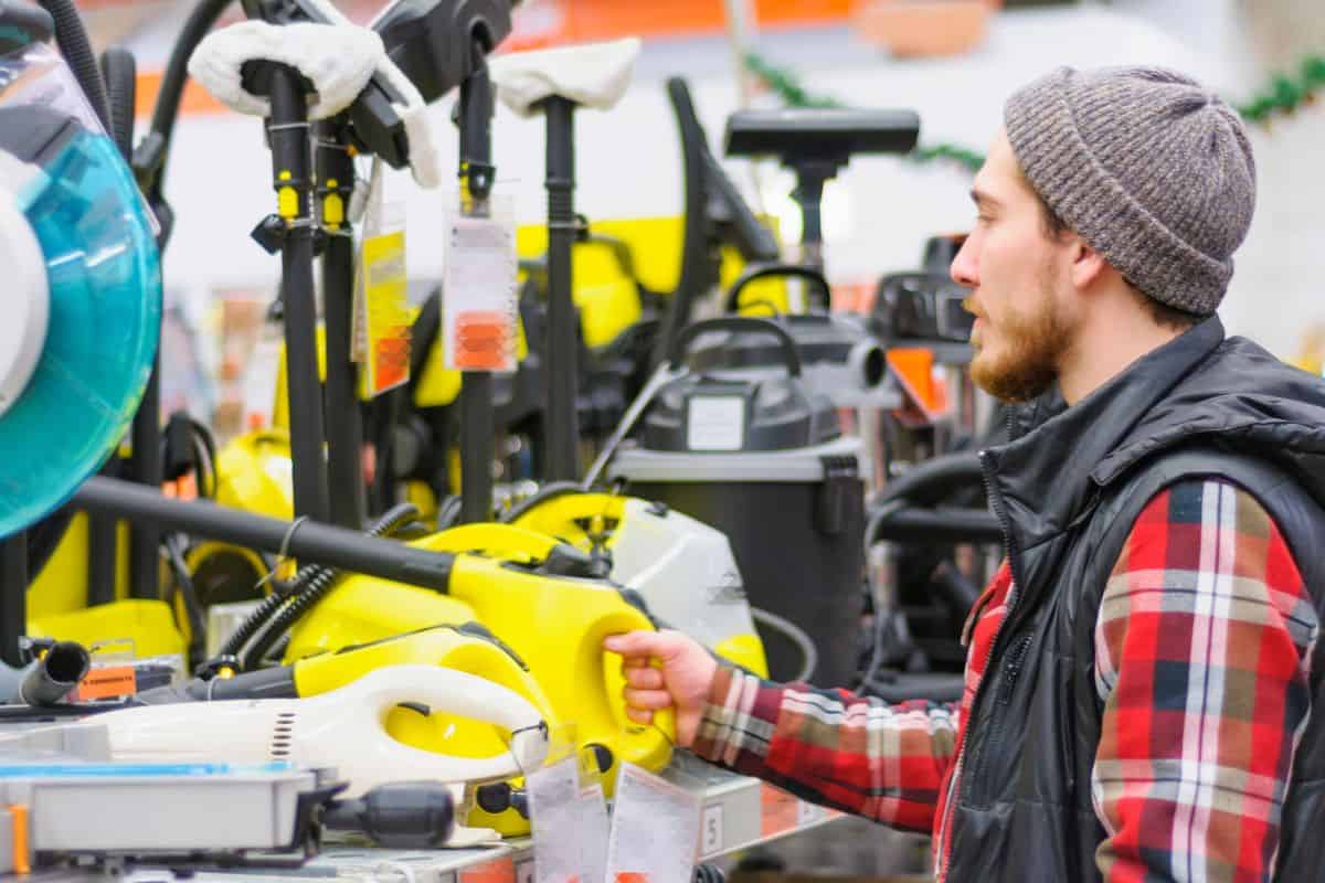 A young man chooses a high pressure washer in the hardware store