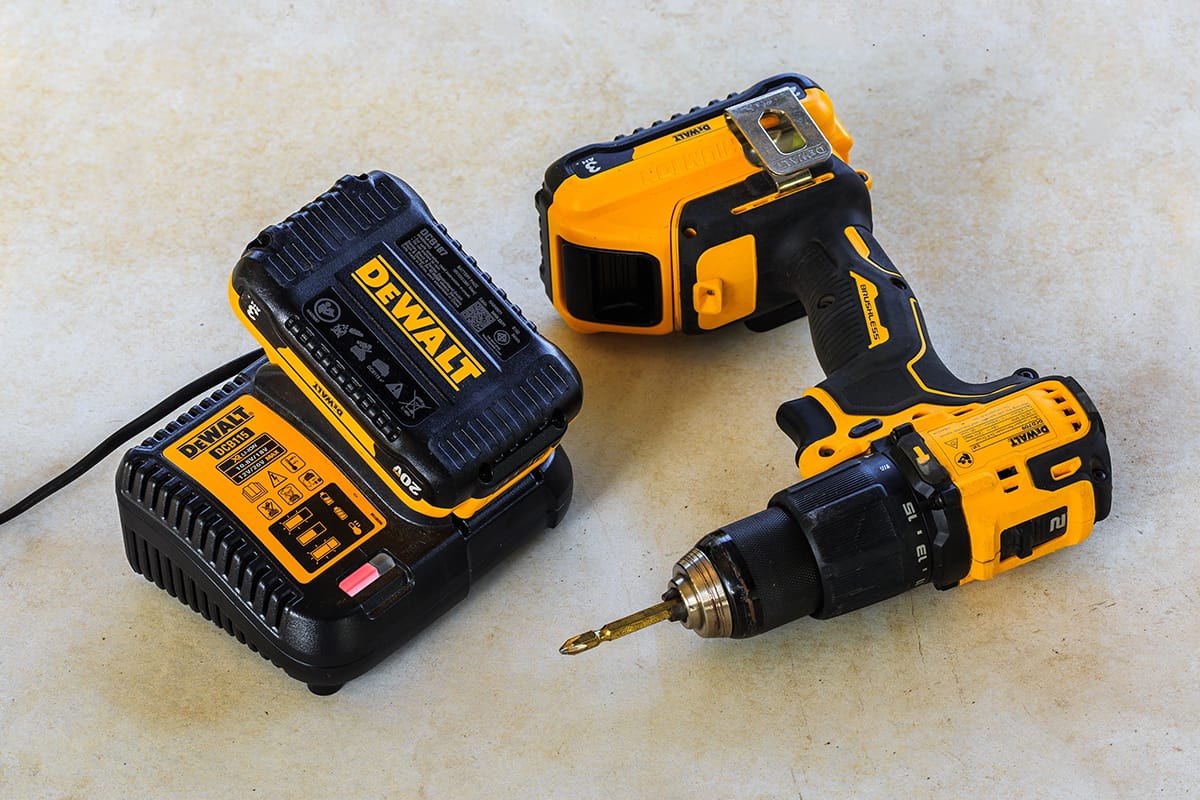 Dewalt cordless hammer drill-driver with battery charger and second battery on cement board