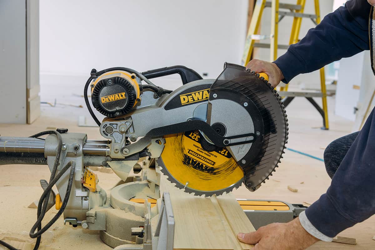 Worker cutting wood baseboard on the power saw