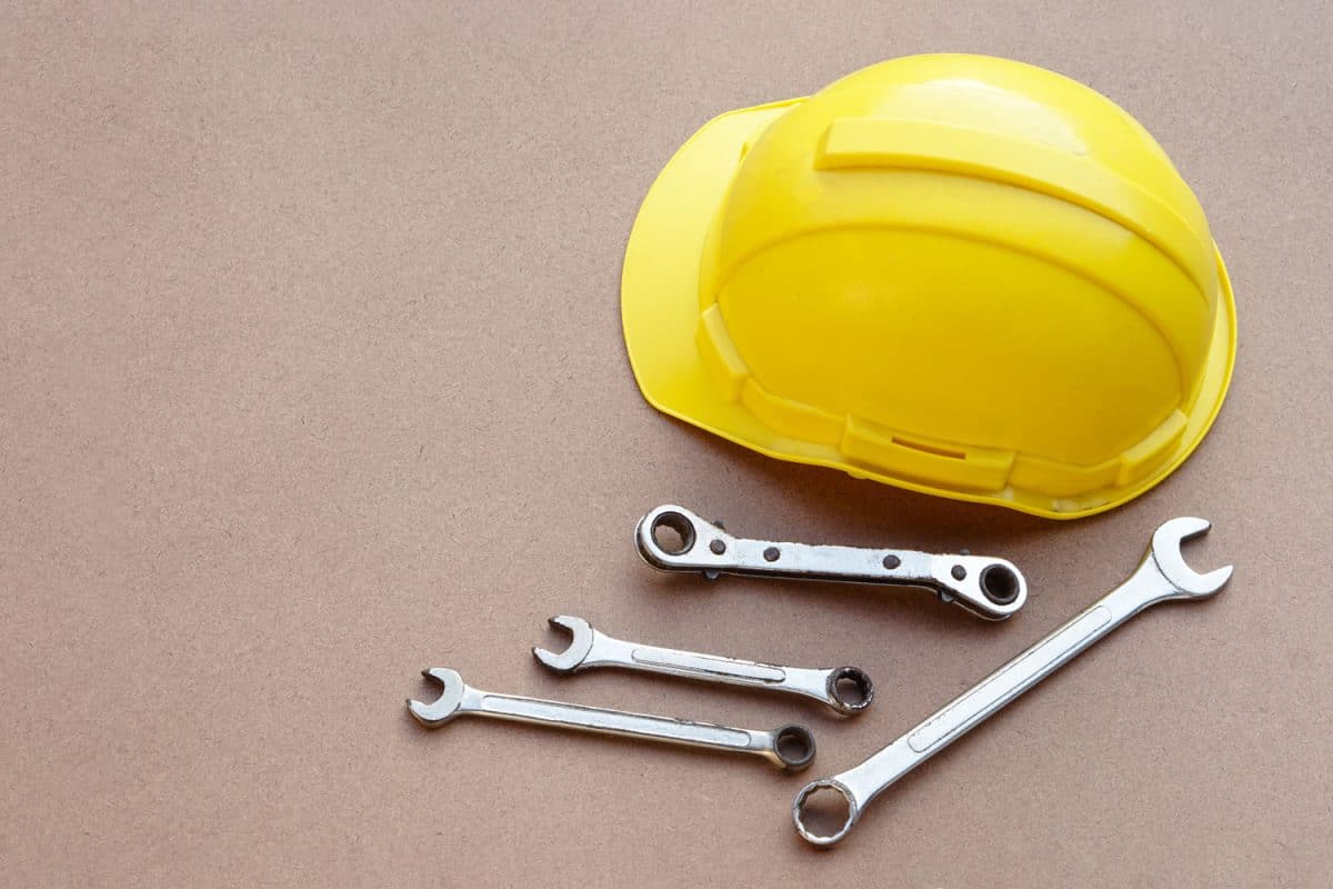 Yellow helmet and wrenches on brown background