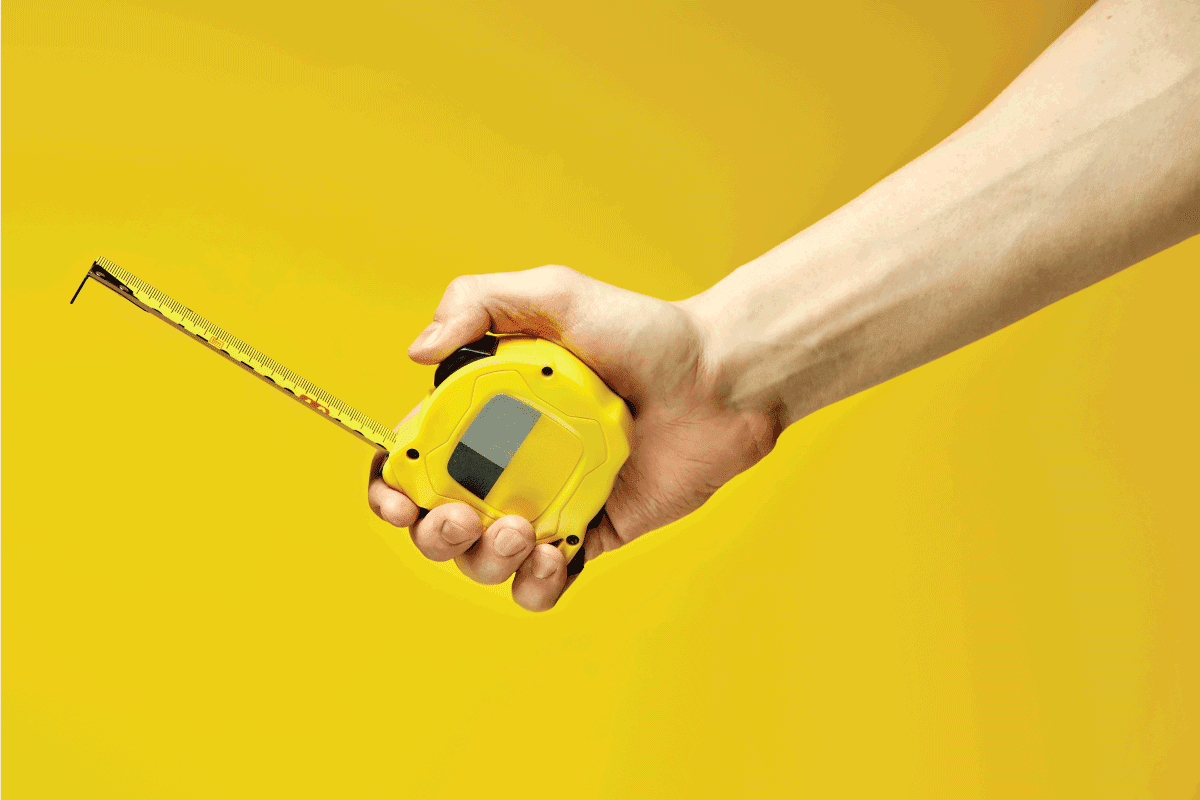 carpenter measuring tape with an imperial units scale isolated on yellow background