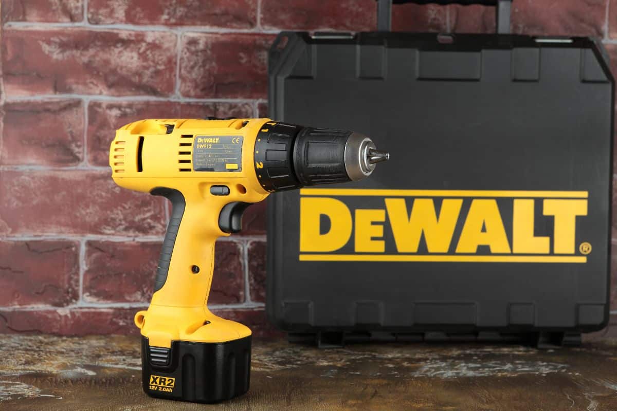 12V Cordless Drill/Drivers DeWalt DW912 on a wooden table against a brick wall.