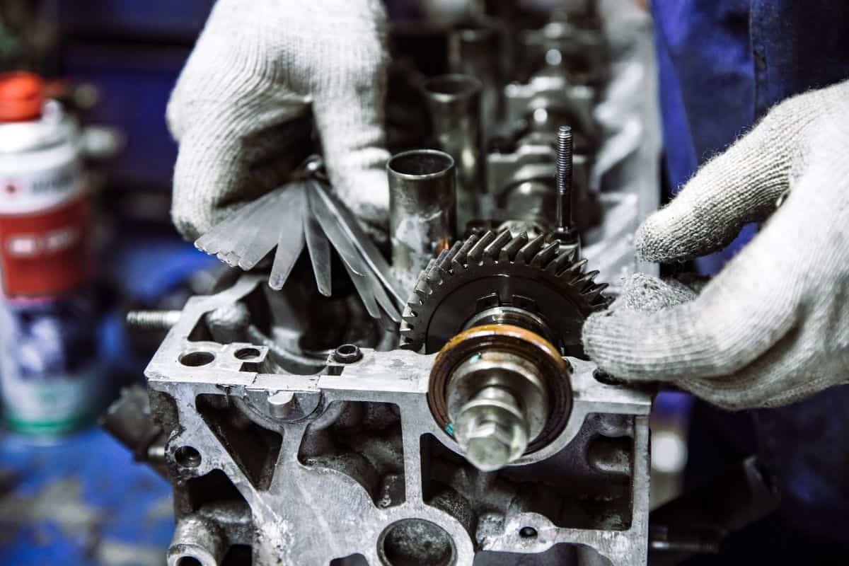 Camshaft of an internal combustion engine and a worker's hand with gloves and a device for adjusting at a shallow depth of field