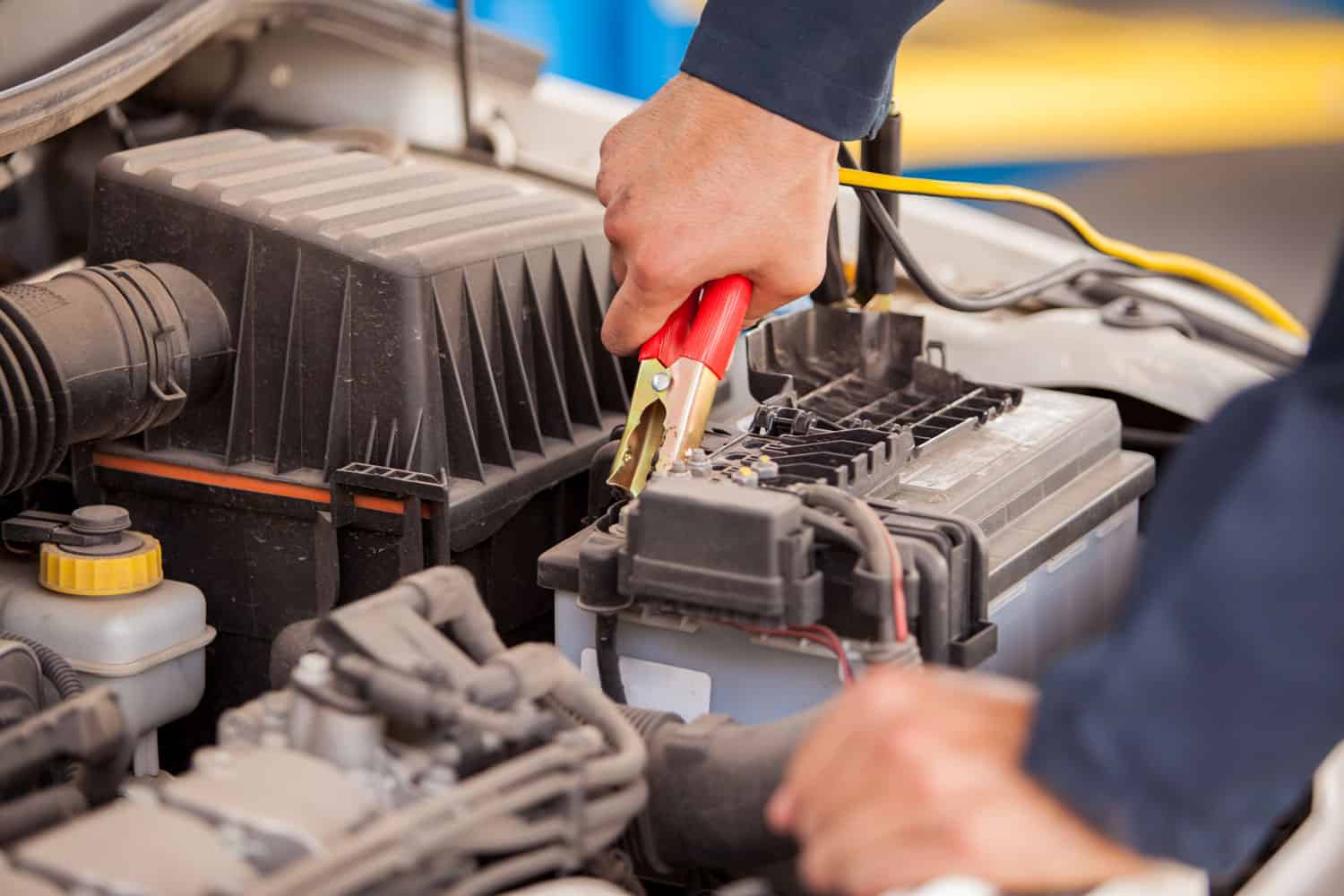 Closeup of the hands of a mechanic using jumper cables to start a car 